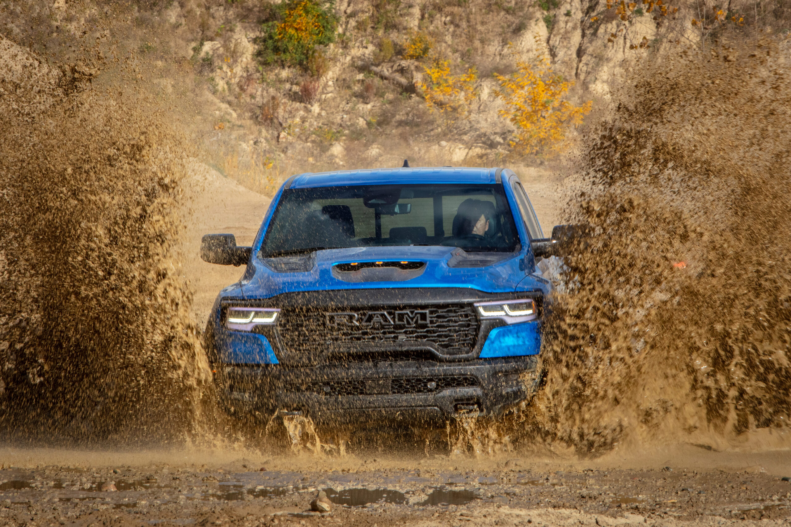 2025 Ram 1500 RHO in blue splashing through deep water and mud