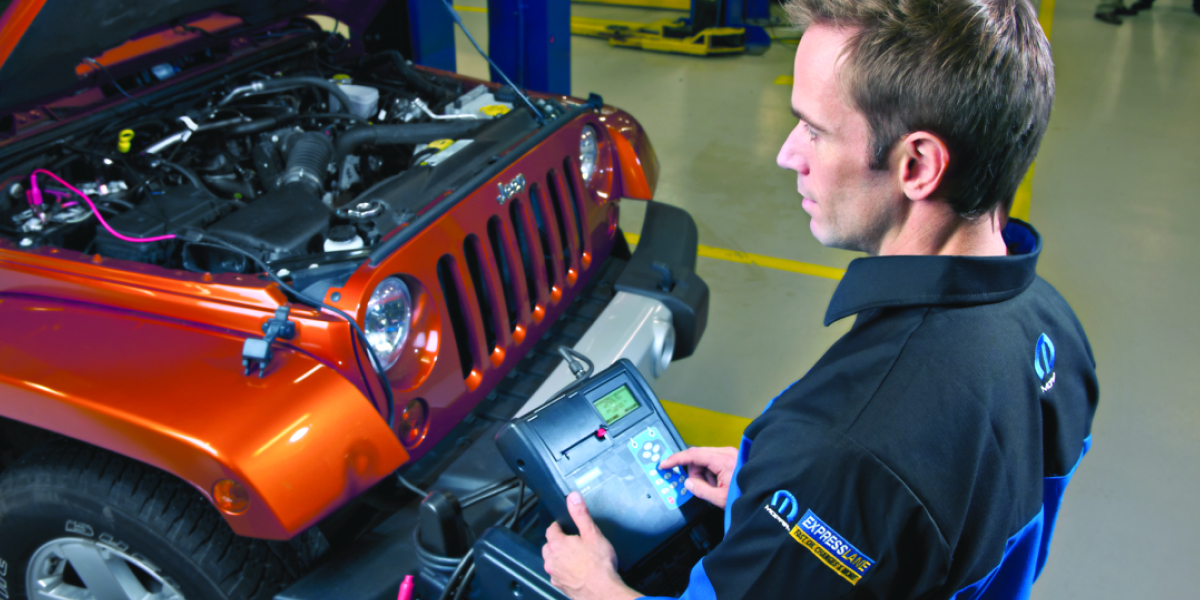 Service technician in a Mopar Express Lane uniform using a handheld diagnostic tester on an orange Jeep Wrangler with the hood open in a dealership service bay.